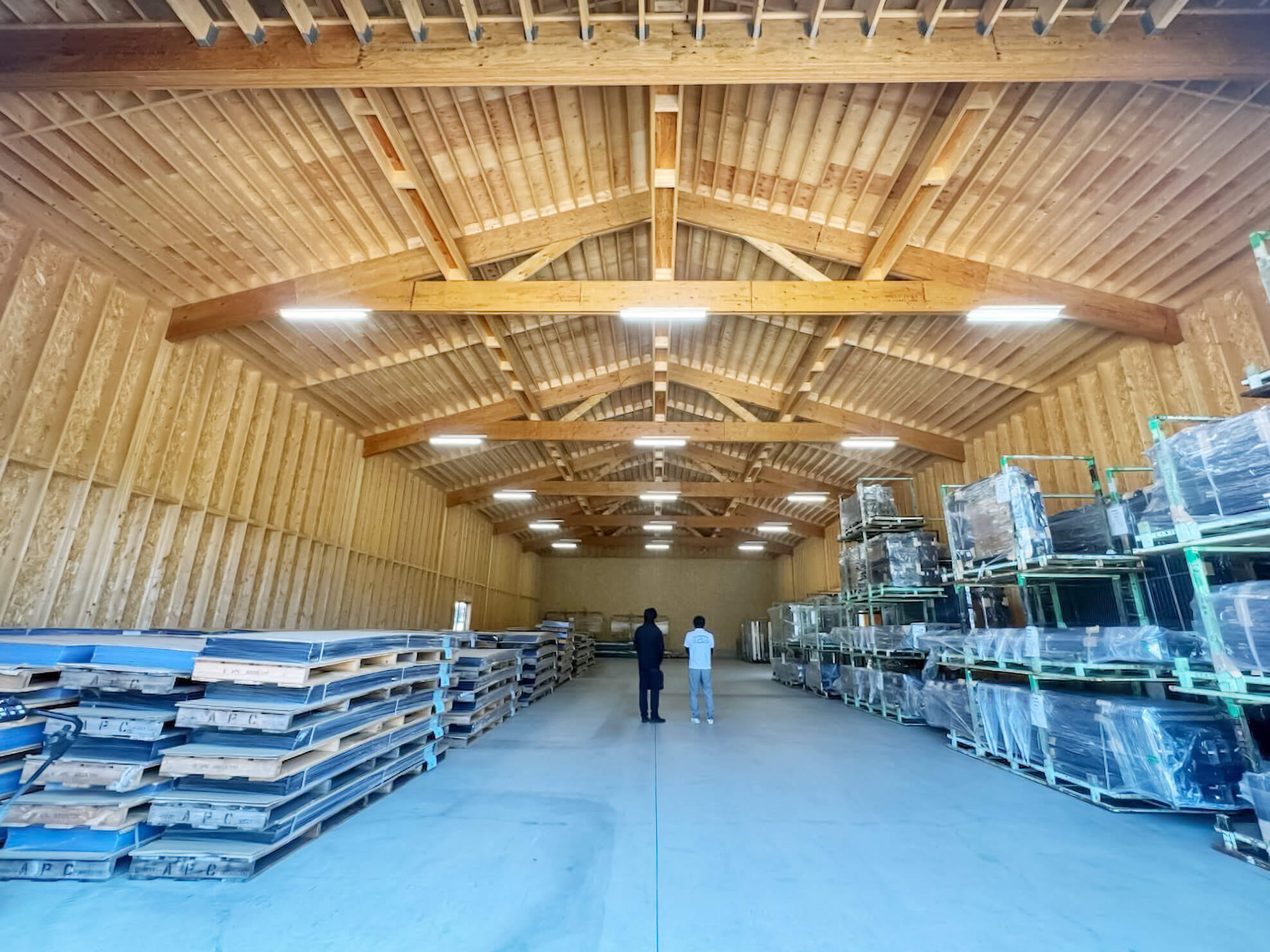 木造倉庫の完成後の内部で、資材ラックと保管物が並ぶ様子