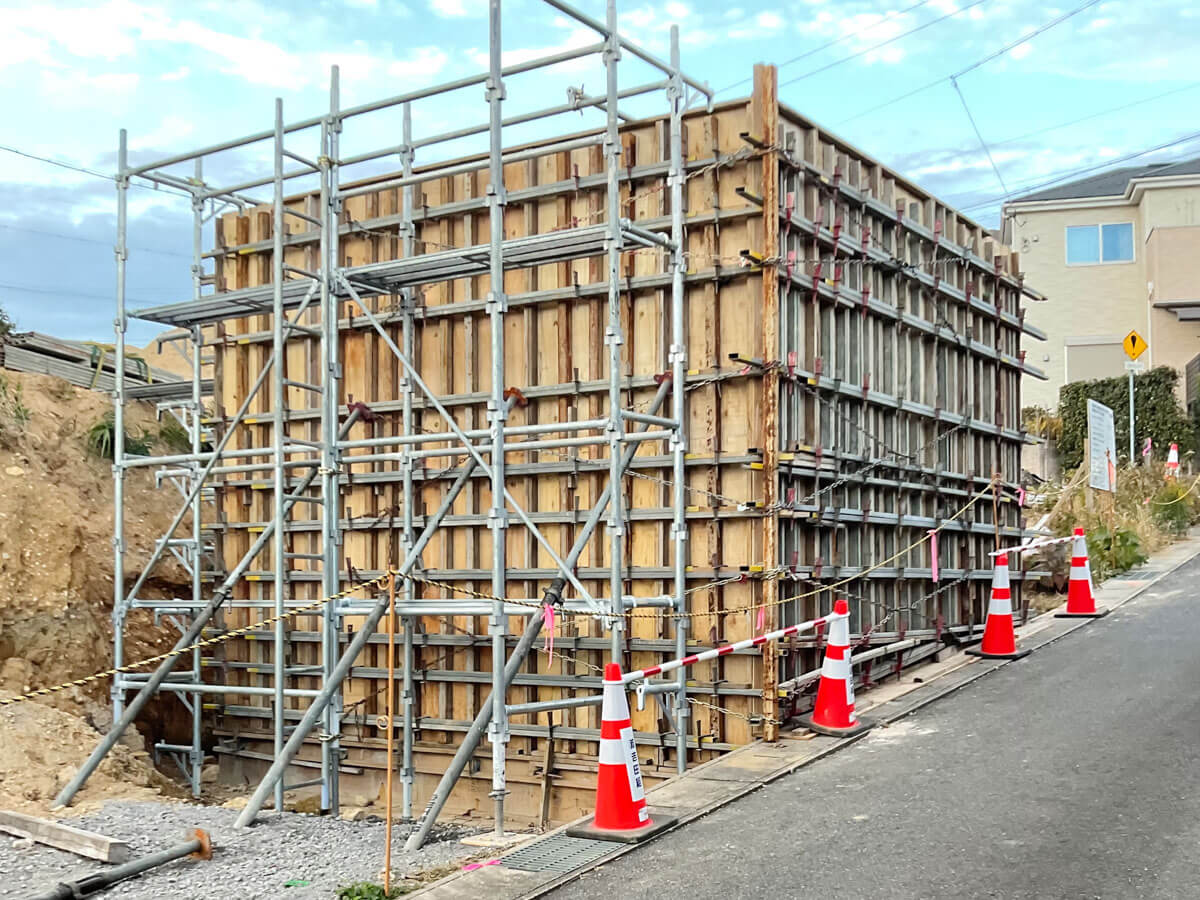 道路沿いの基礎工事で、木製型枠と足場により囲われた構造物